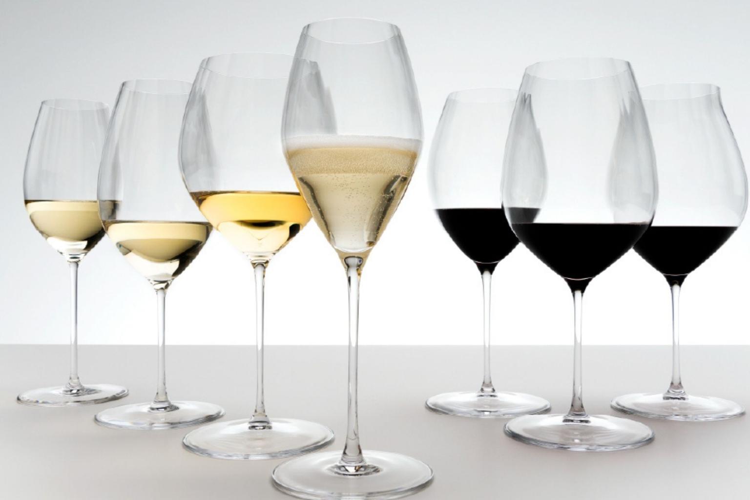 Assorted wine glasses with white and red wine, evenly spaced on a light surface.