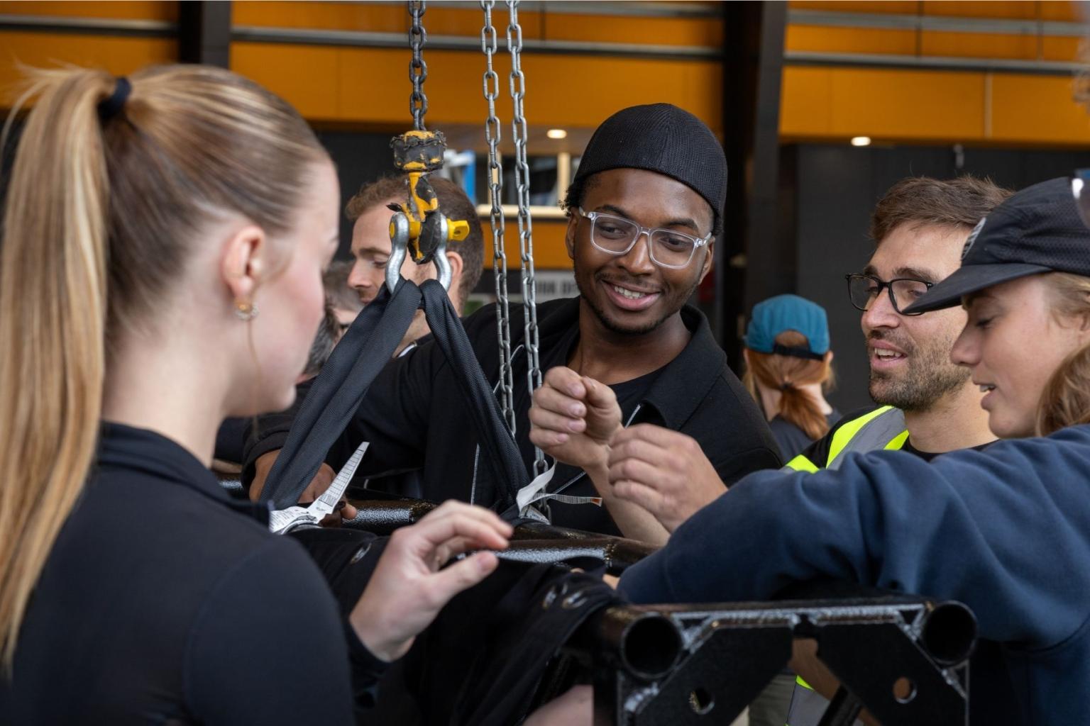 People collaborating on a project with rigging equipment, indoors.