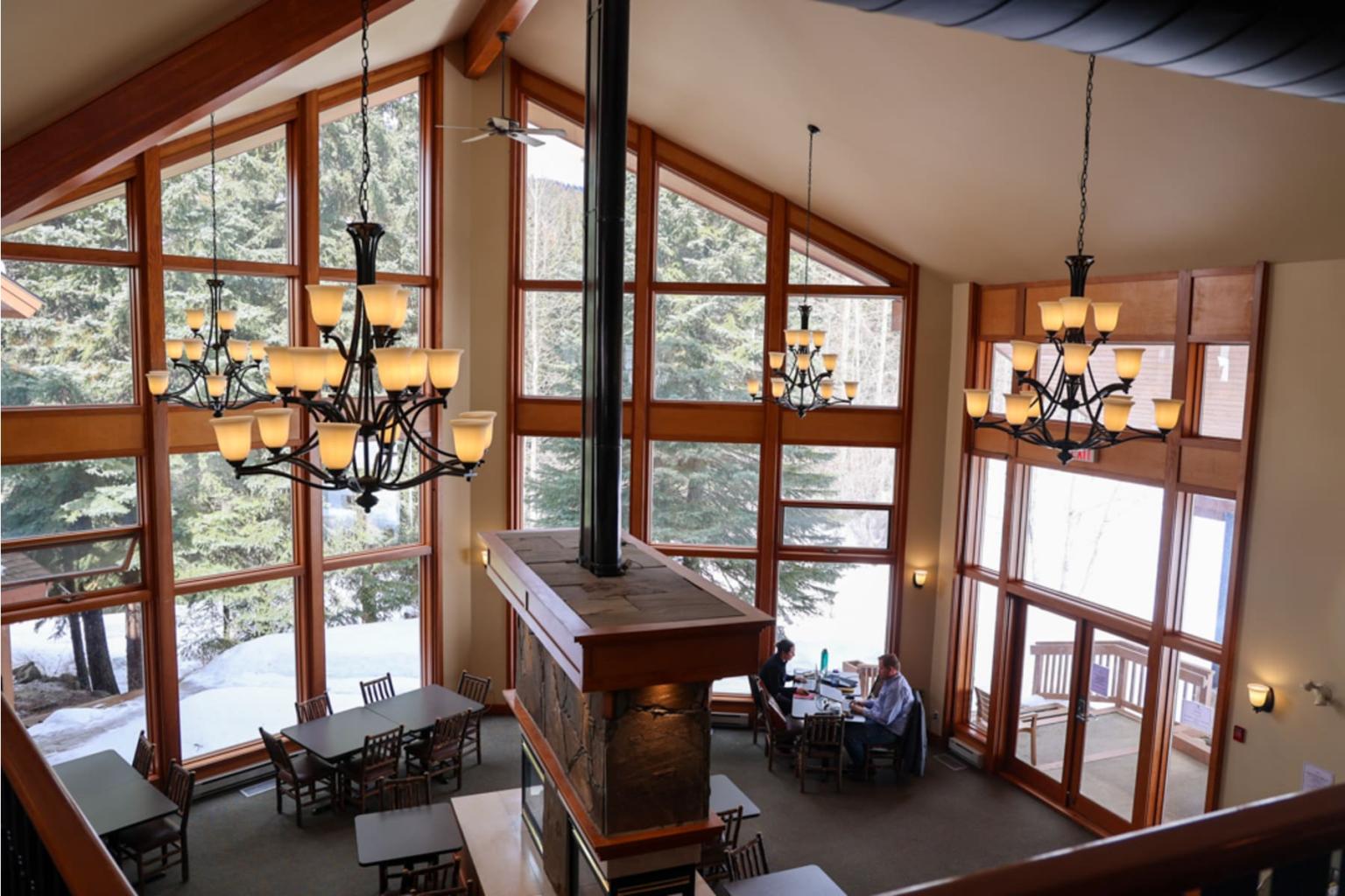 Spacious lodge interior with large windows and chandeliers.