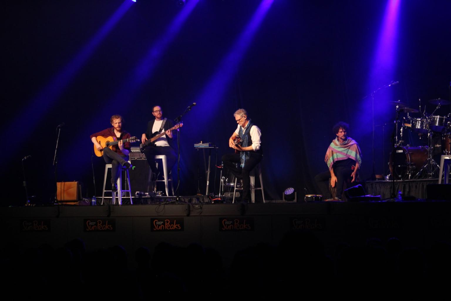 Musicians perform on stage under blue lighting.