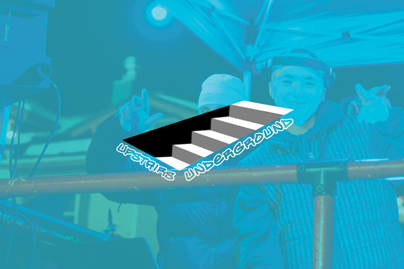 DJ performing under blue lighting with logo overlay.