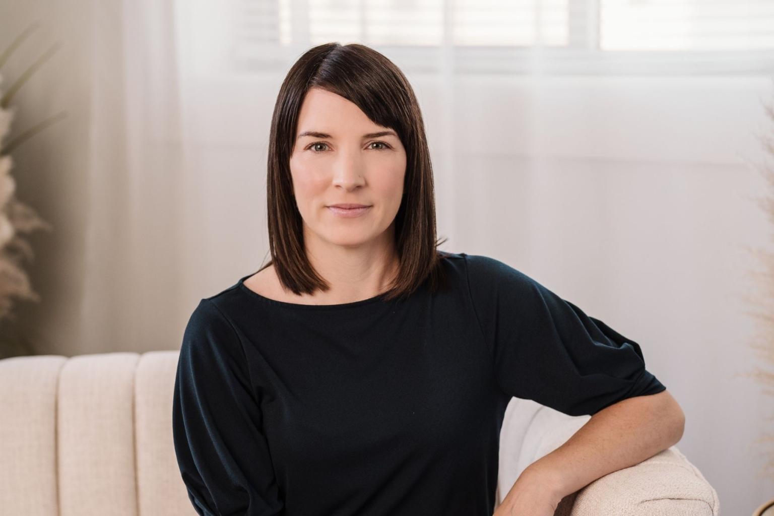 Woman sitting on a sofa in a softly lit room.