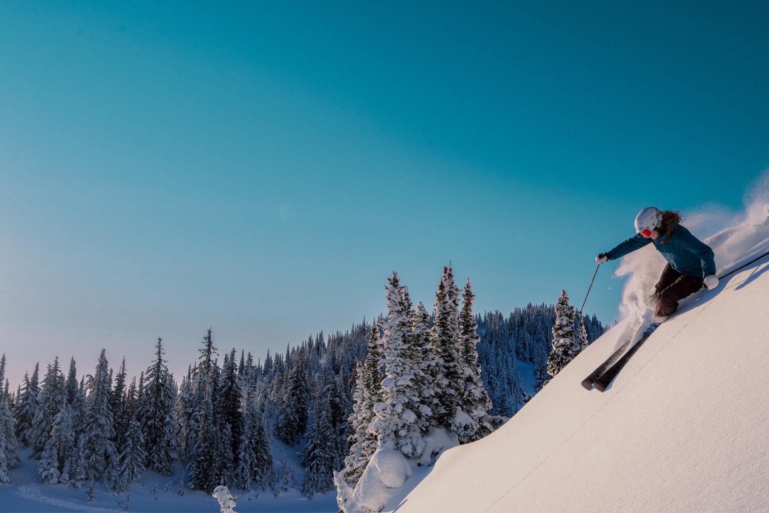 Skiing down a snowy slope under a clear blue sky.