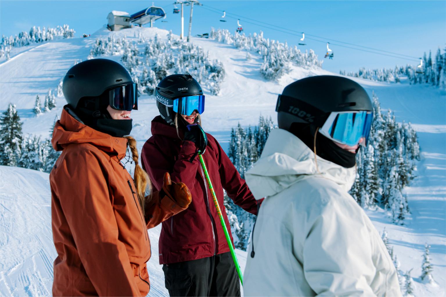 Skiers in helmets on a snowy mountain with clear blue skies.