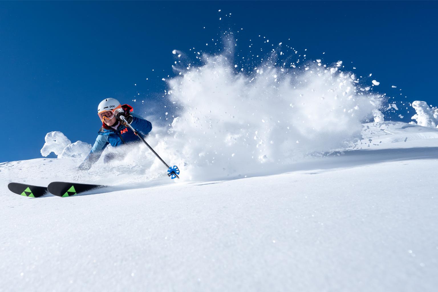 Skier carving through snow on a sunny day.