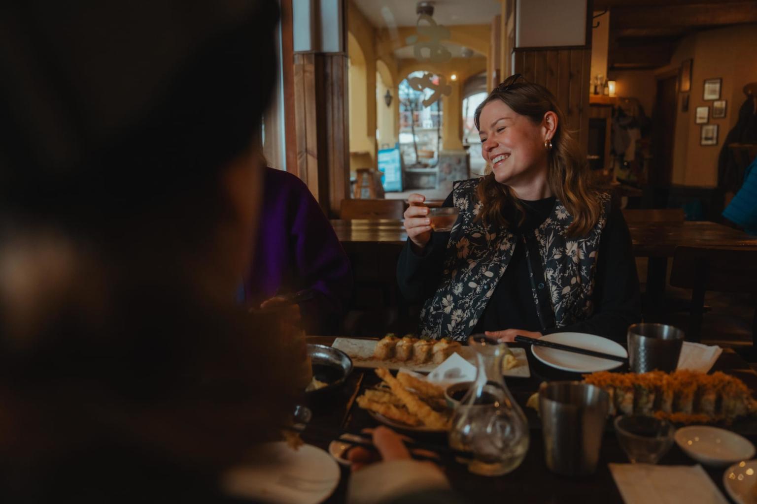 Smiling woman enjoying a meal at a cozy restaurant table.