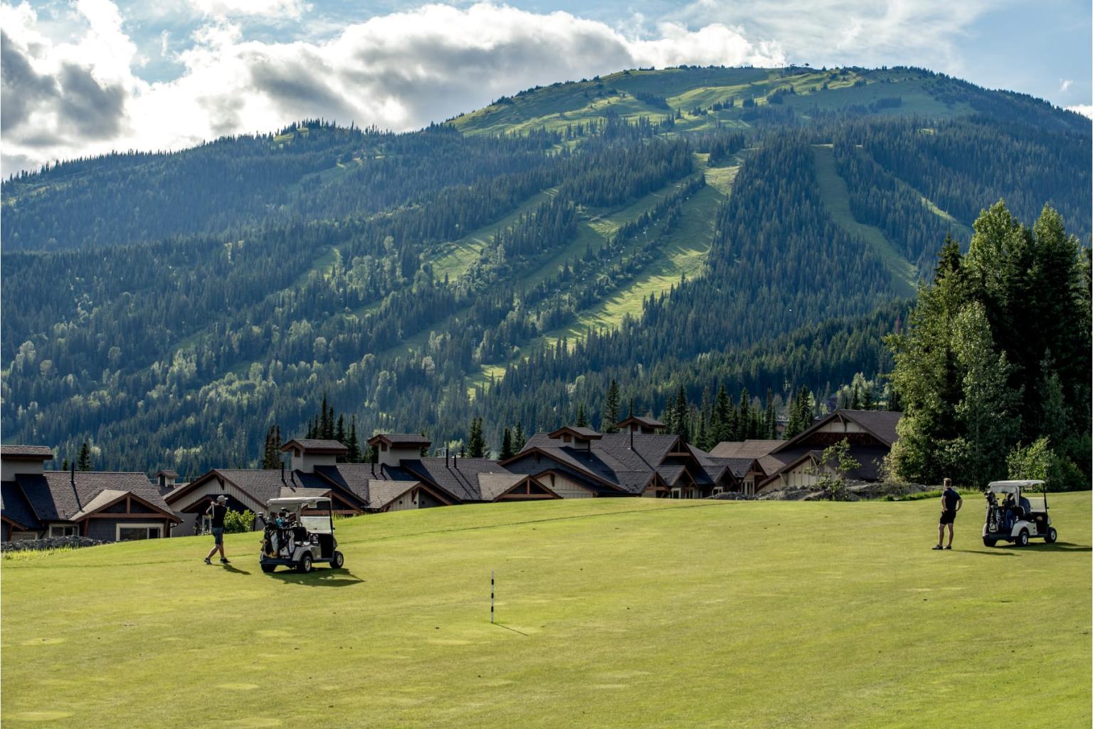 Golf course with mountains in the background, cloudy sky.