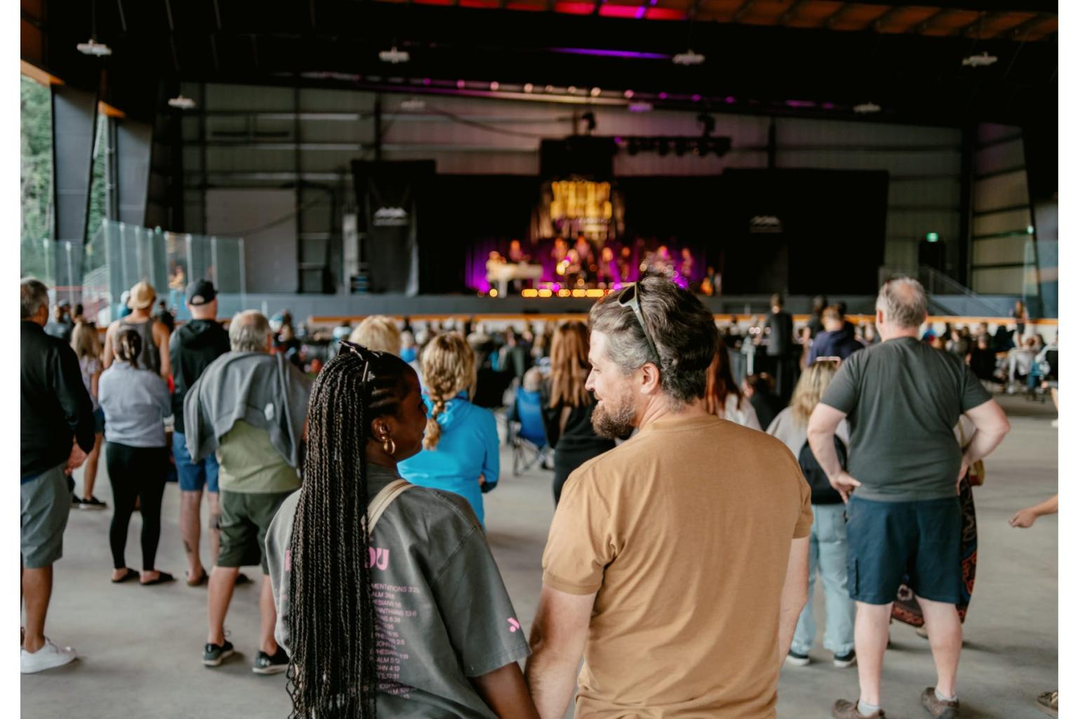 People watching a concert in an indoor venue with colorful stage lights.