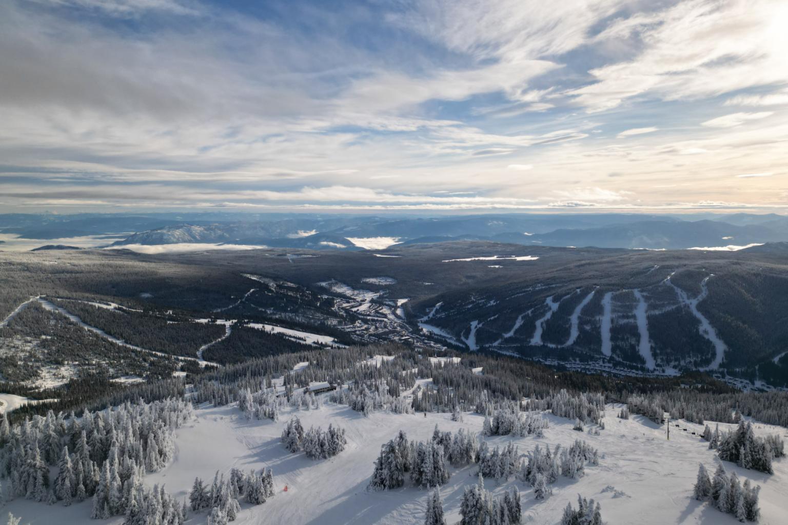 Snowy mountain landscape with ski slopes and cloudy sky.