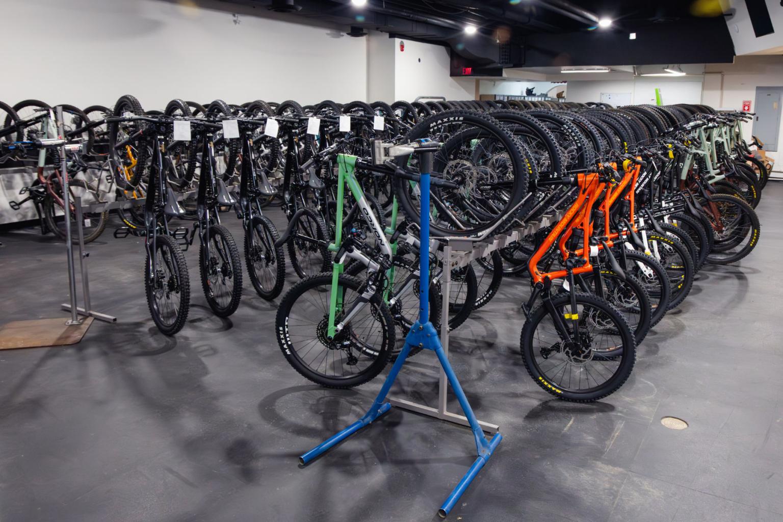 A room filled with multiple mountain bikes on display stands.