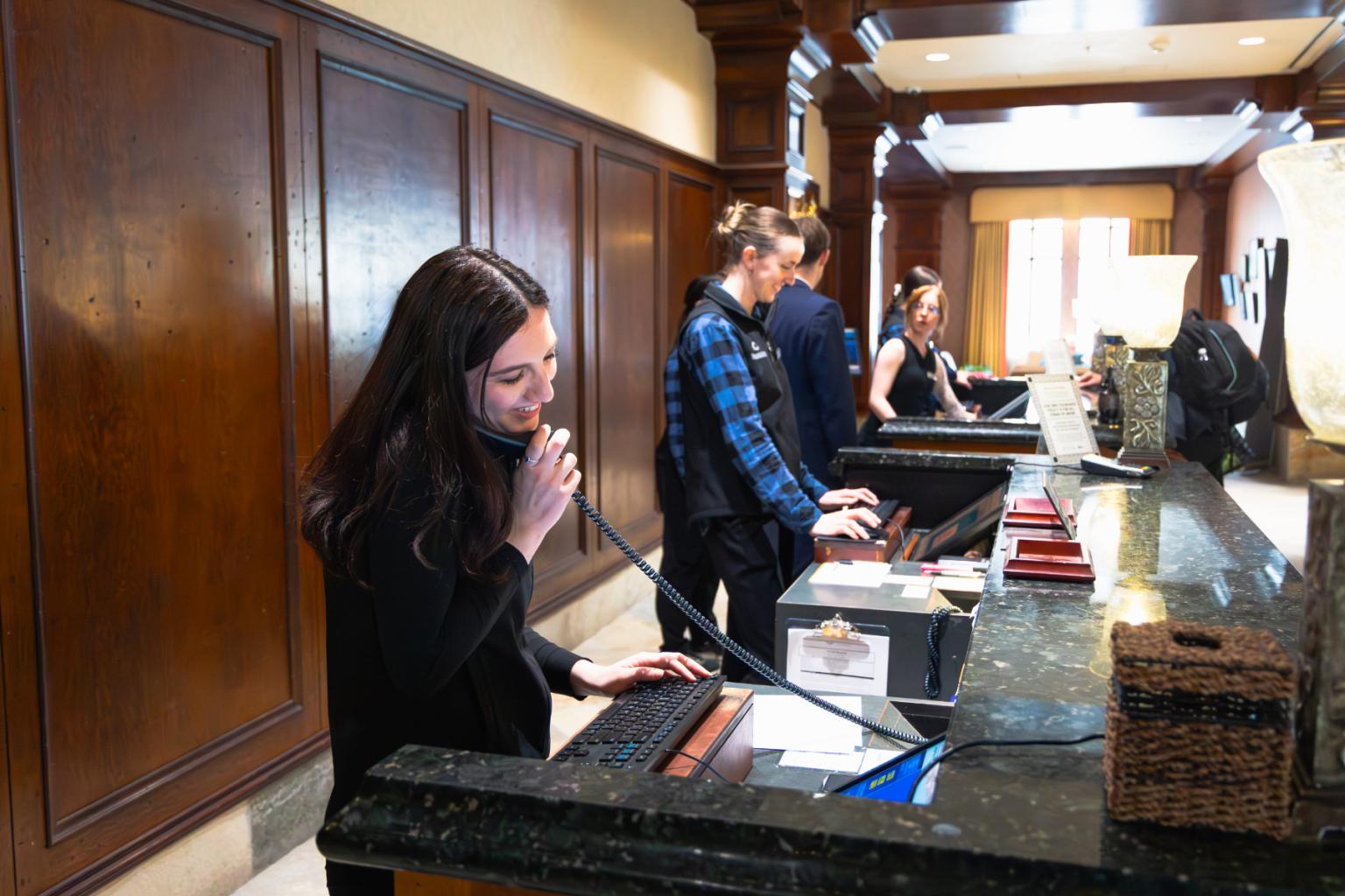 Hotel receptionists assisting guests at a counter.