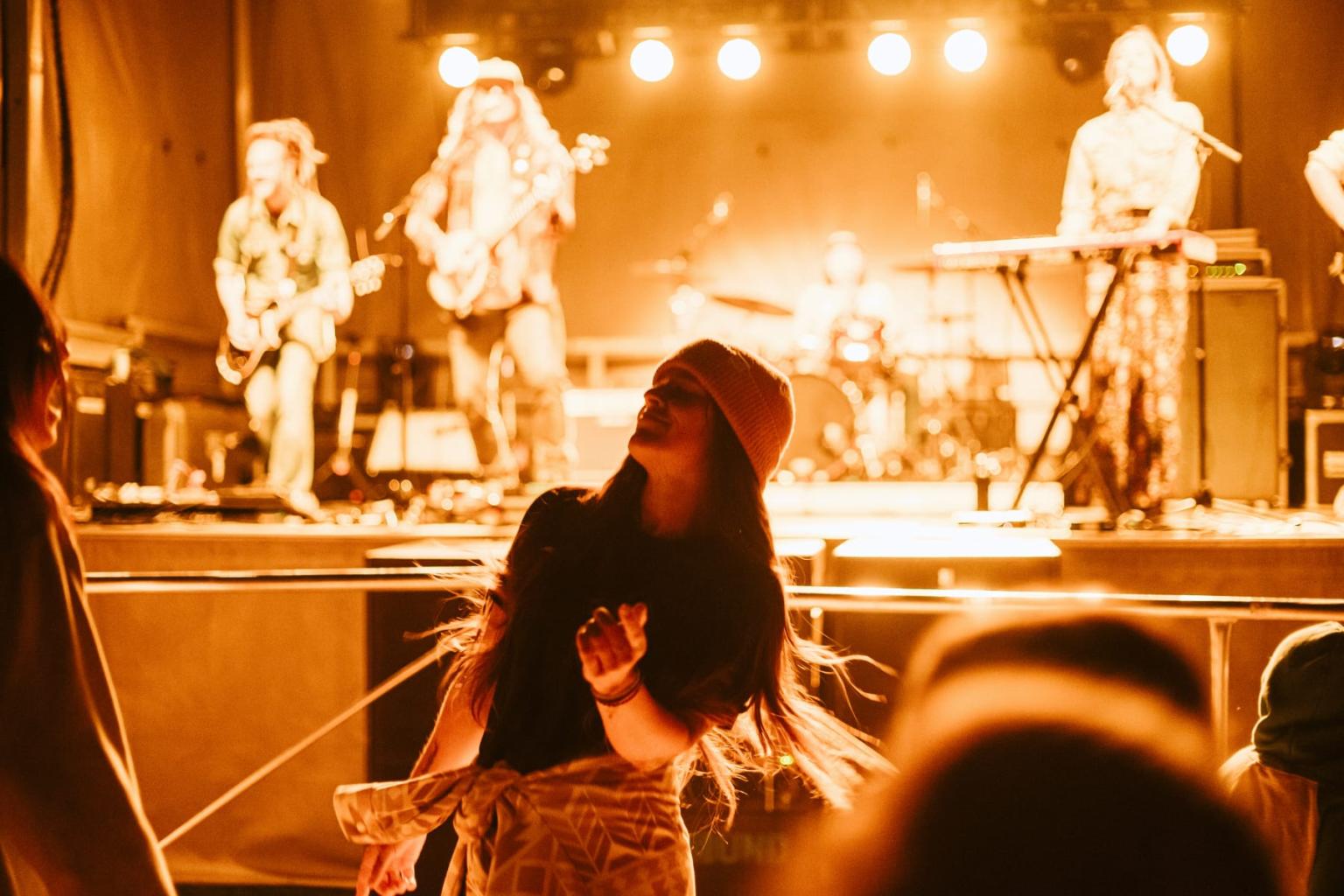 Concert scene with a band on stage, silhouetted person dancing in the foreground.
