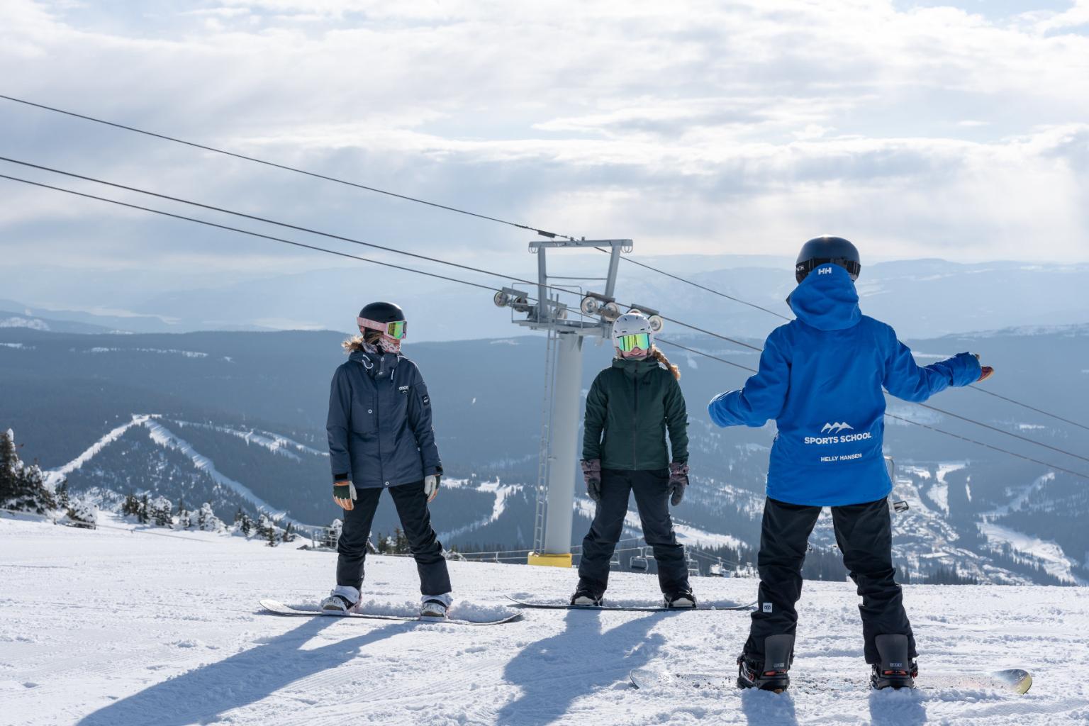 Three skiers in winter gear on a snowy mountain with chairlift.