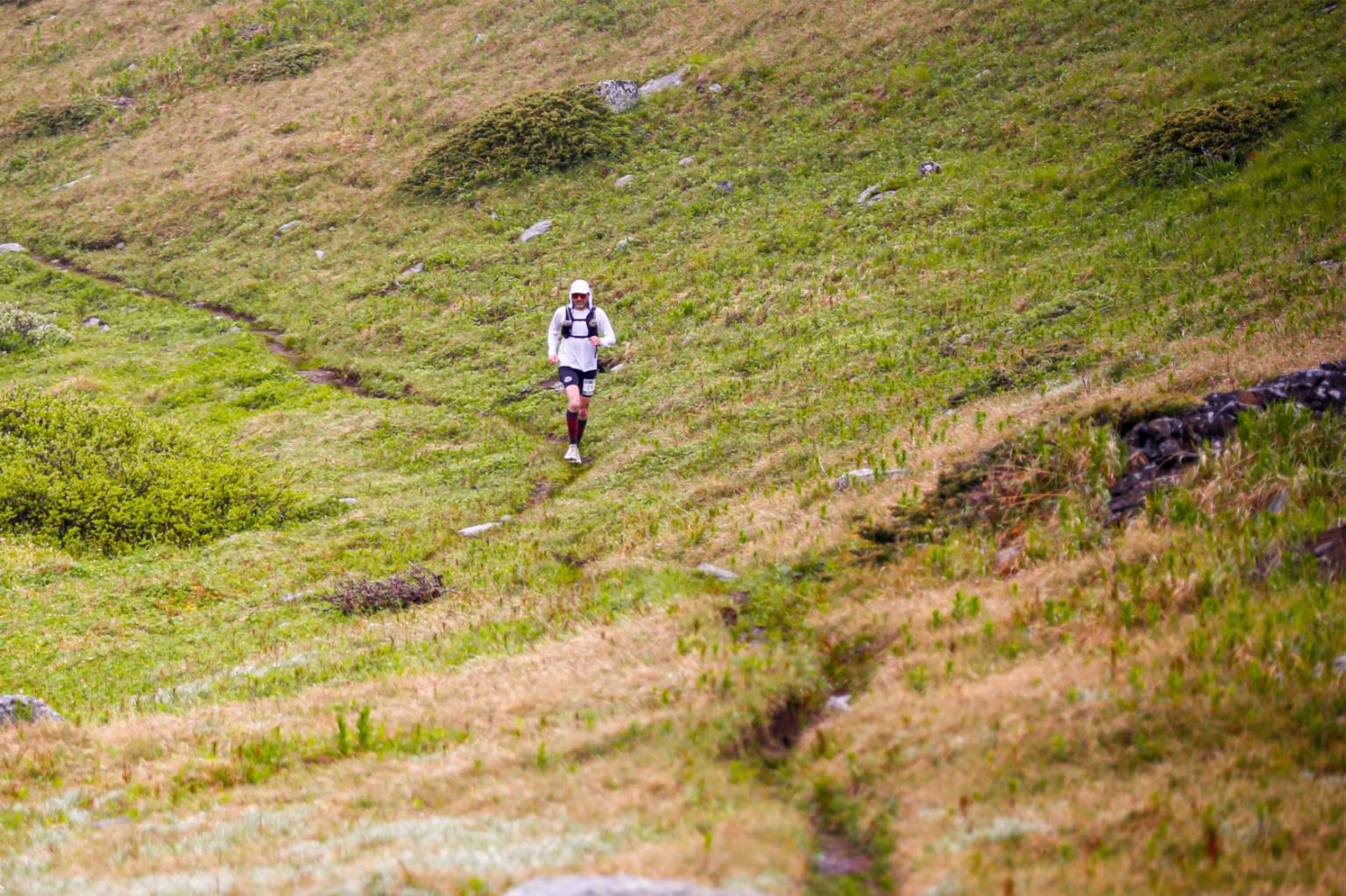 Trail runner in a grassy landscape.