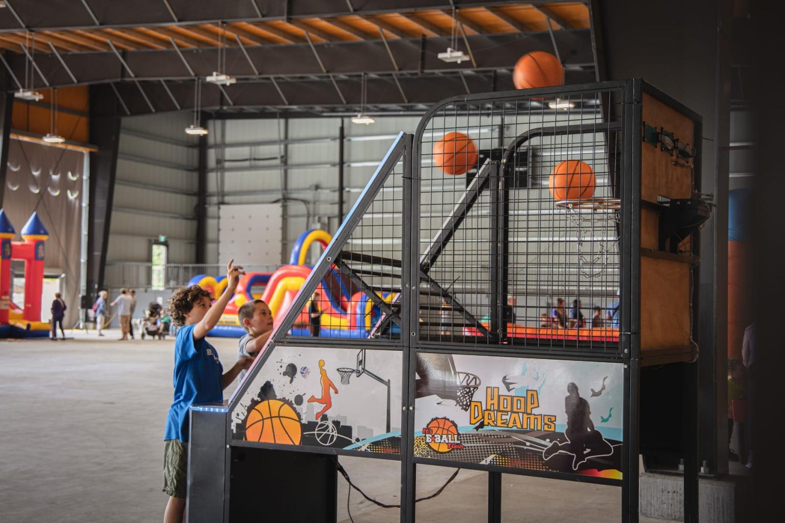 Boy playing basketball arcade game indoors, aiming at hoop.
