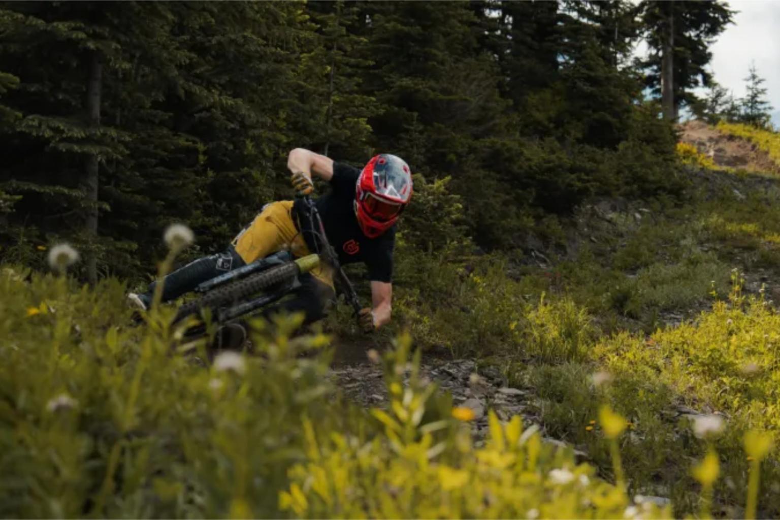 Mountain biker navigating a forest trail, wearing a helmet and colorful gear.