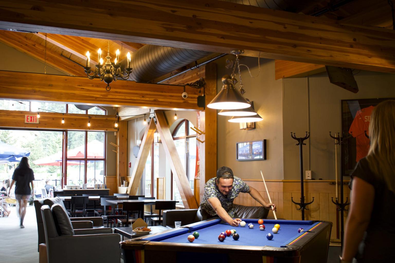 Billiard table in a cozy wooden lounge, man taking a shot.