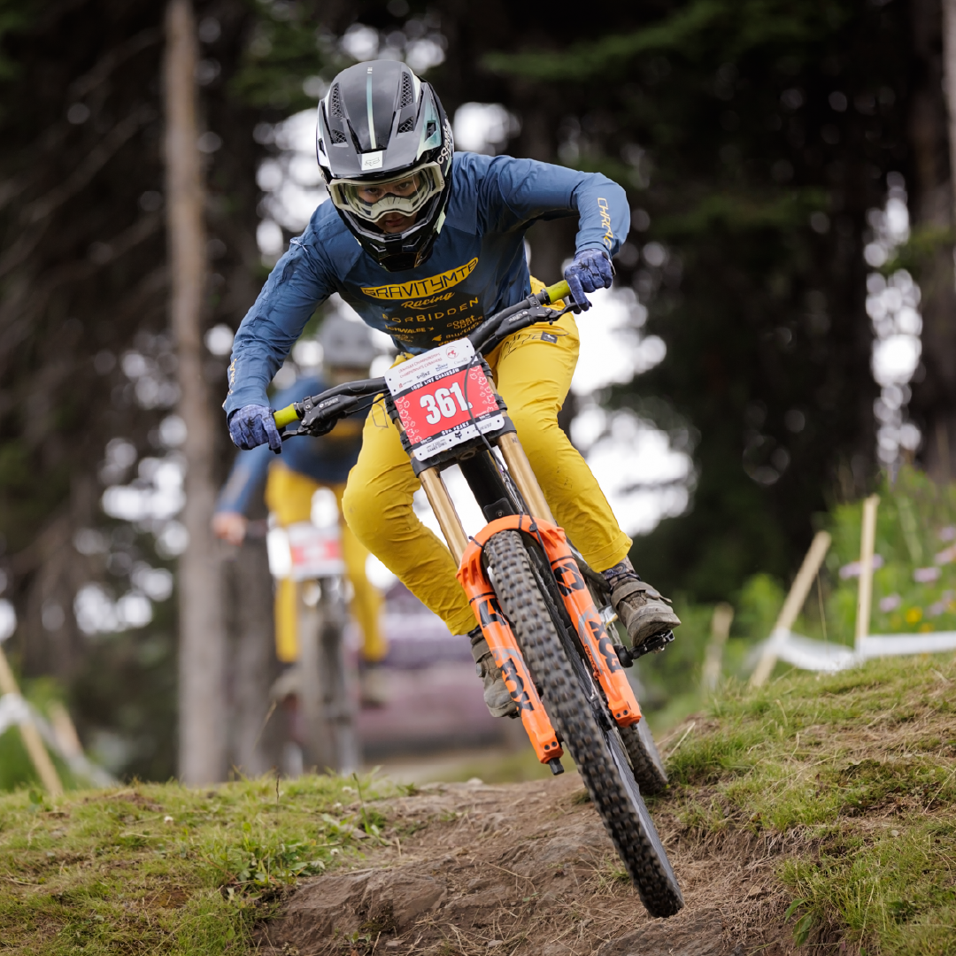 Mountain biker in action on forest trail, wearing helmet and gear.