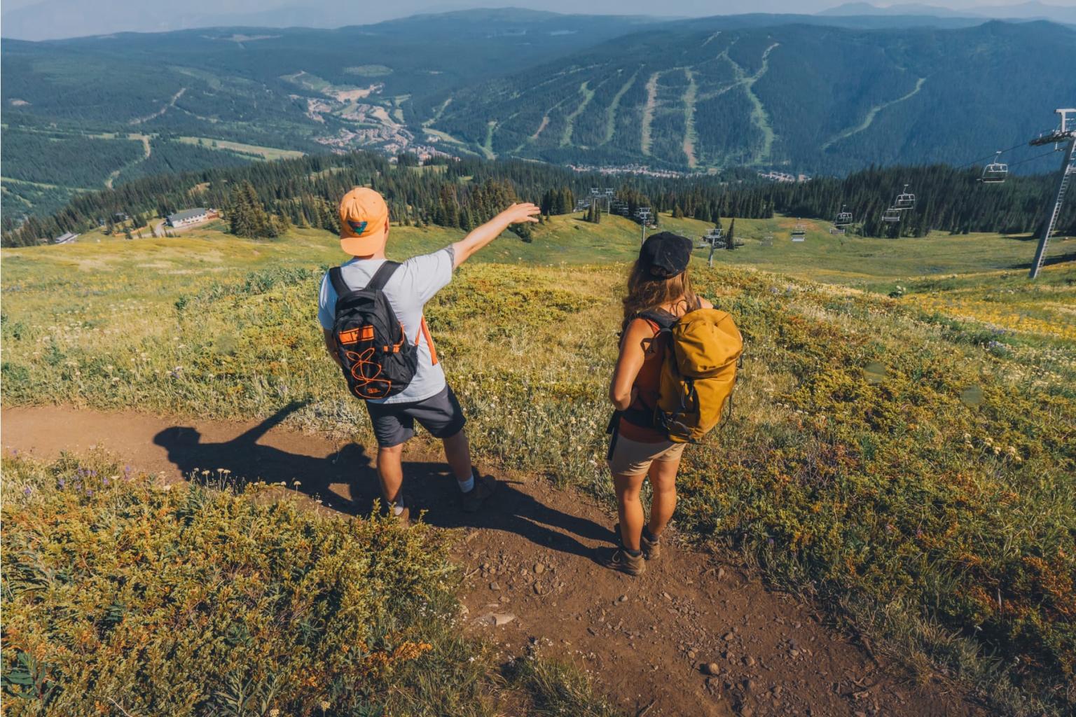 Two hikers on a mountain trail, overlooking a distant valley.