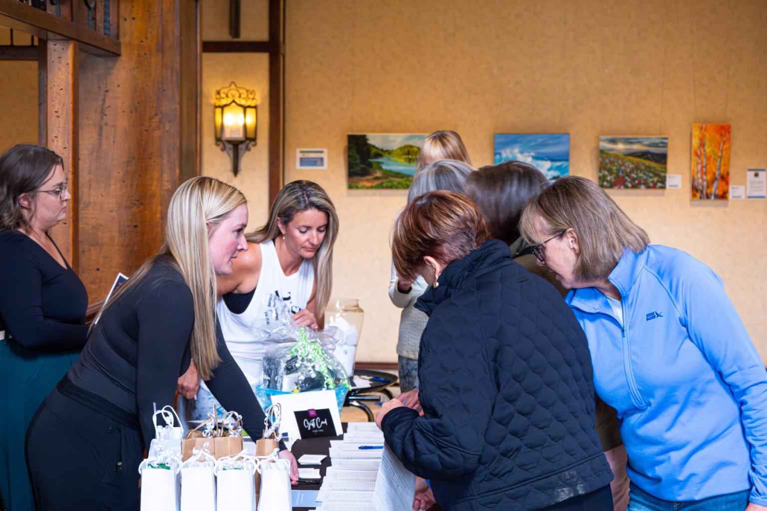 Group of people browsing items at a table indoors.