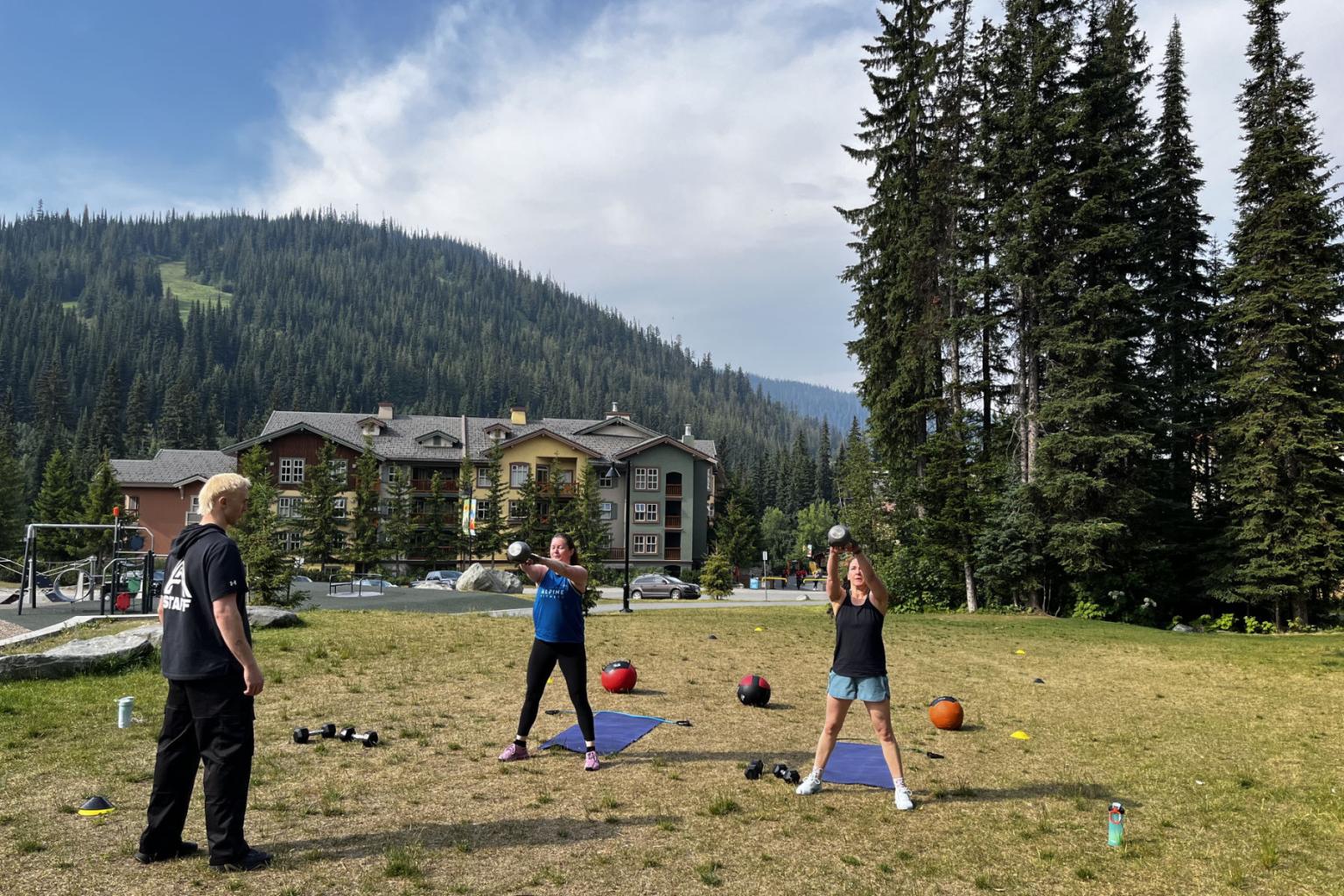People exercising on grass with mountains and trees in the background.