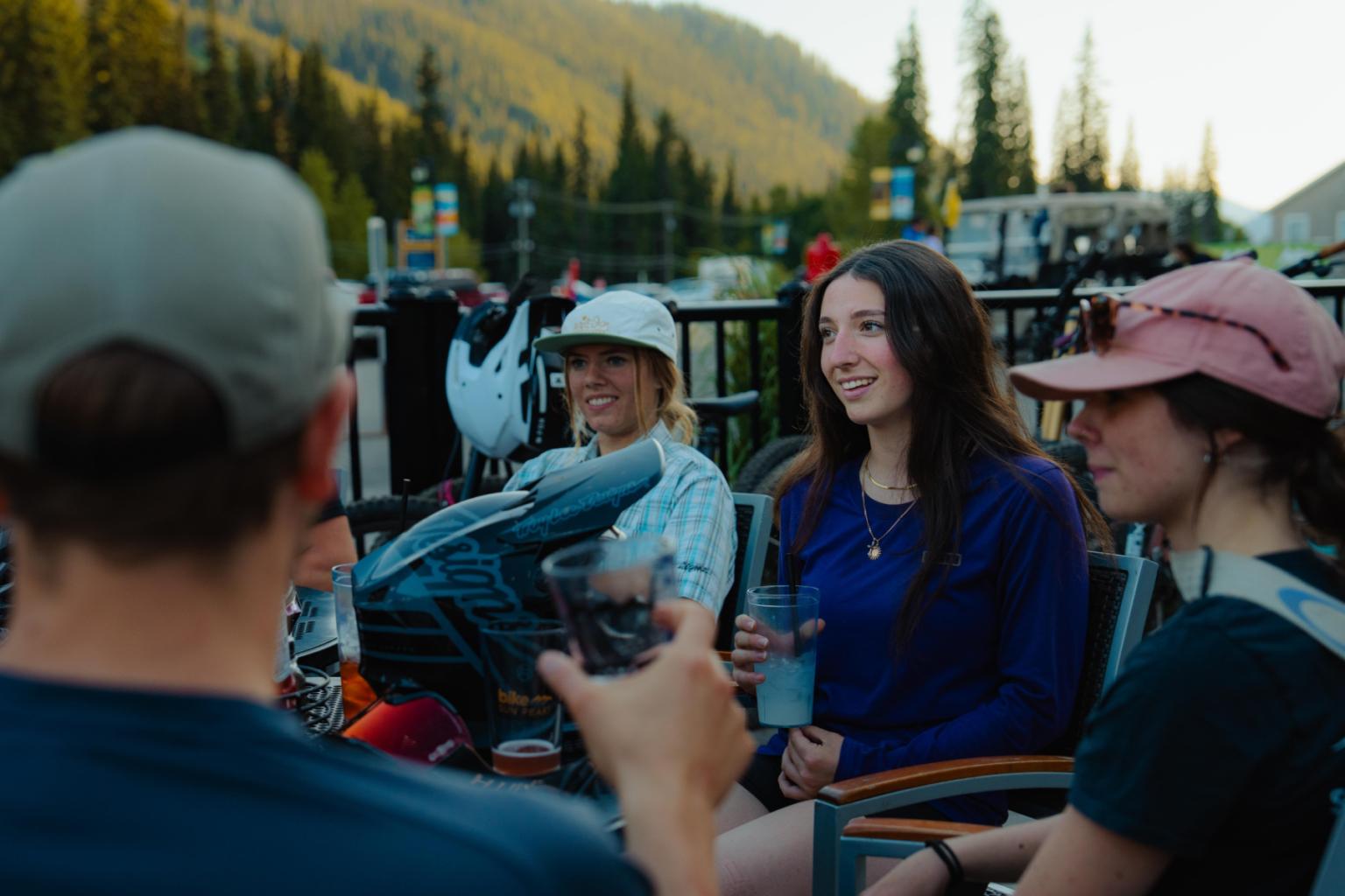 Group relaxing outdoors, smiling, with mountains in the background.