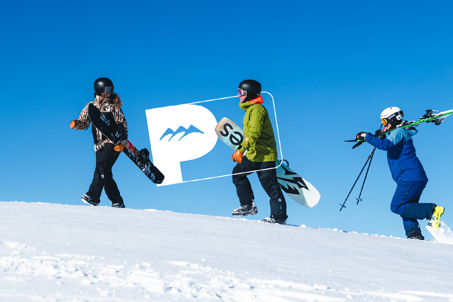 Three people with snowboards and skis on a snowy slope under a clear blue sky.