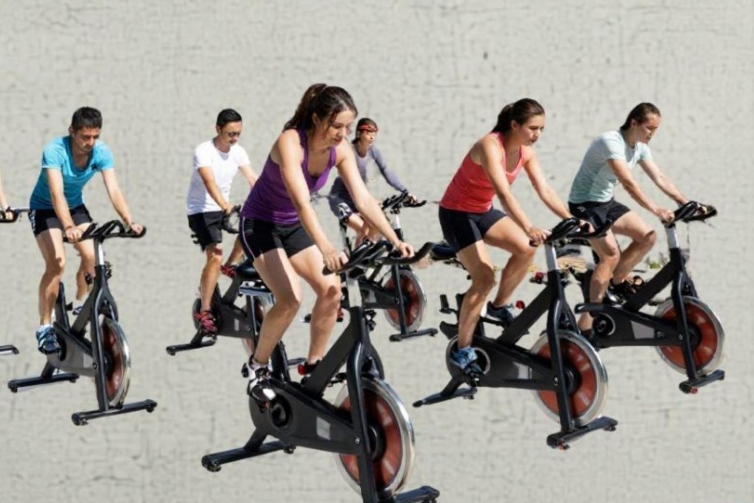 Group of people exercising on stationary bikes.