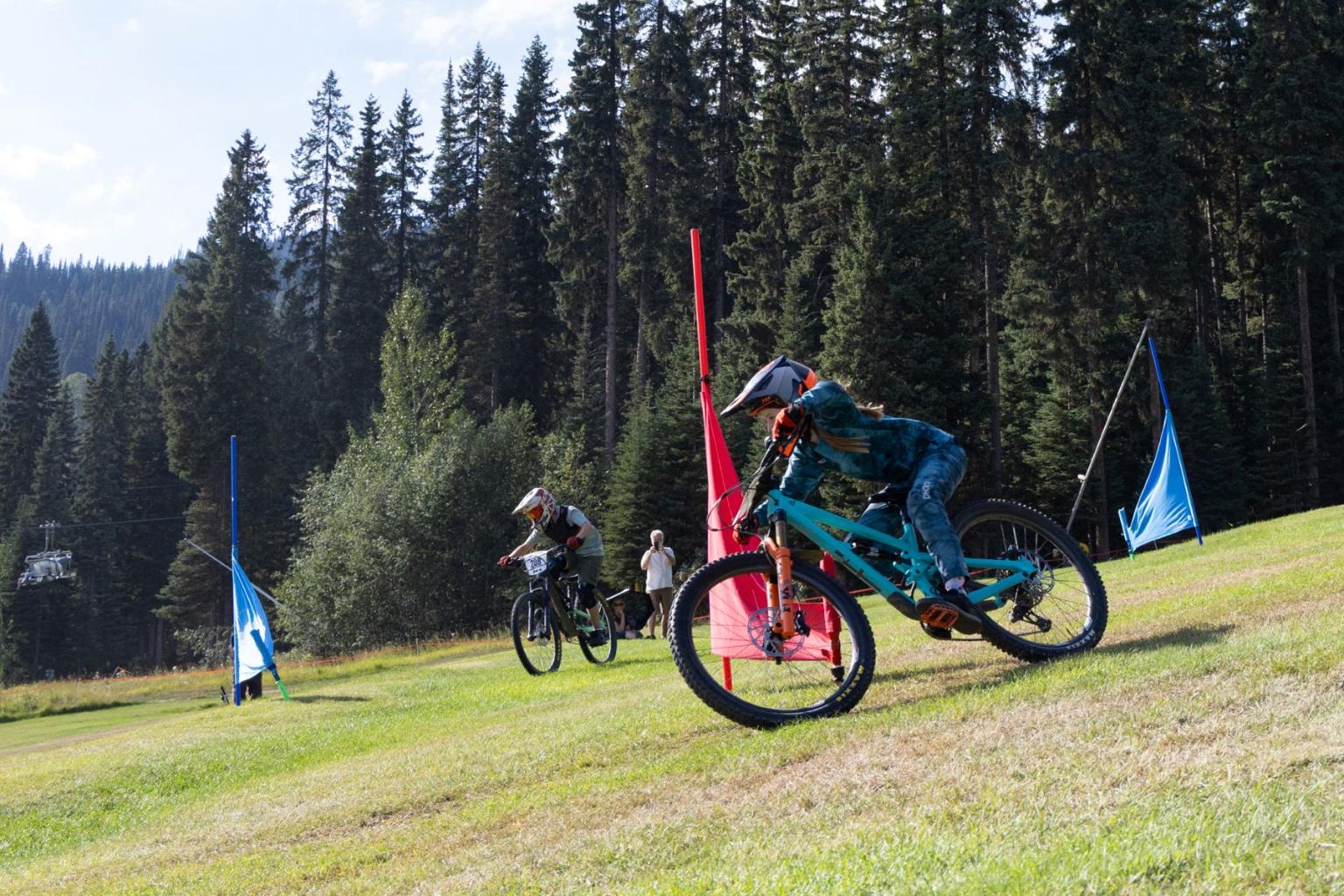Mountain biker racing downhill past red and blue slalom course flags.