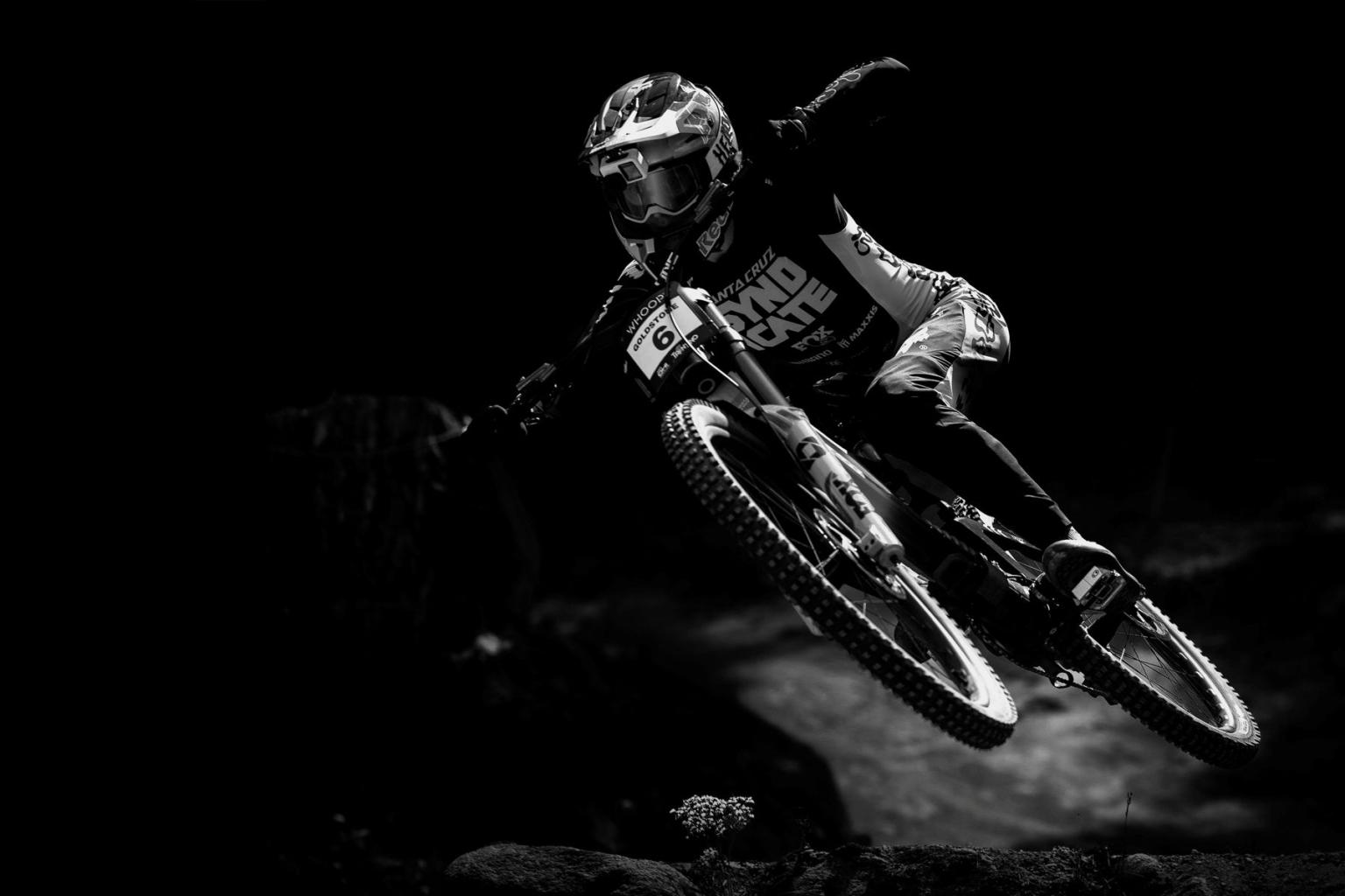 Mountain biker in mid-air, black and white photograph on black background.