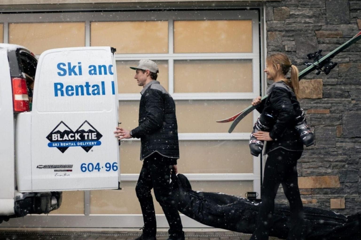 Man and woman delivering ski rental gear in Sun Peaks in falling snow.