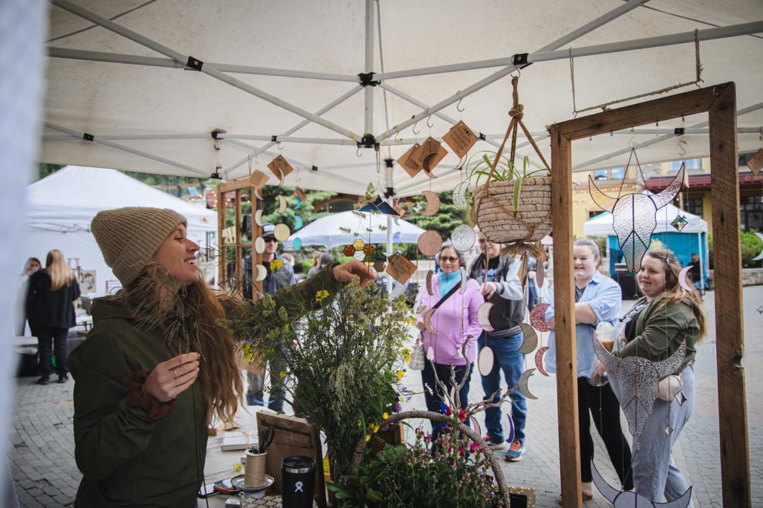 Woman browsing hanging plants at an outdoor market stall