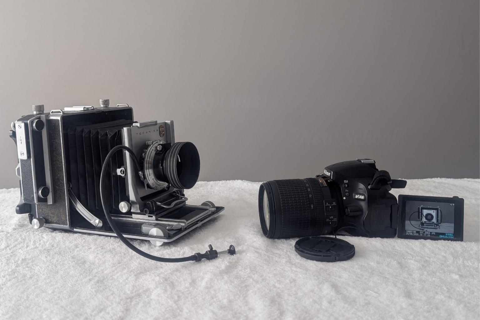 Two vintage cameras on a gray surface against a gray background.