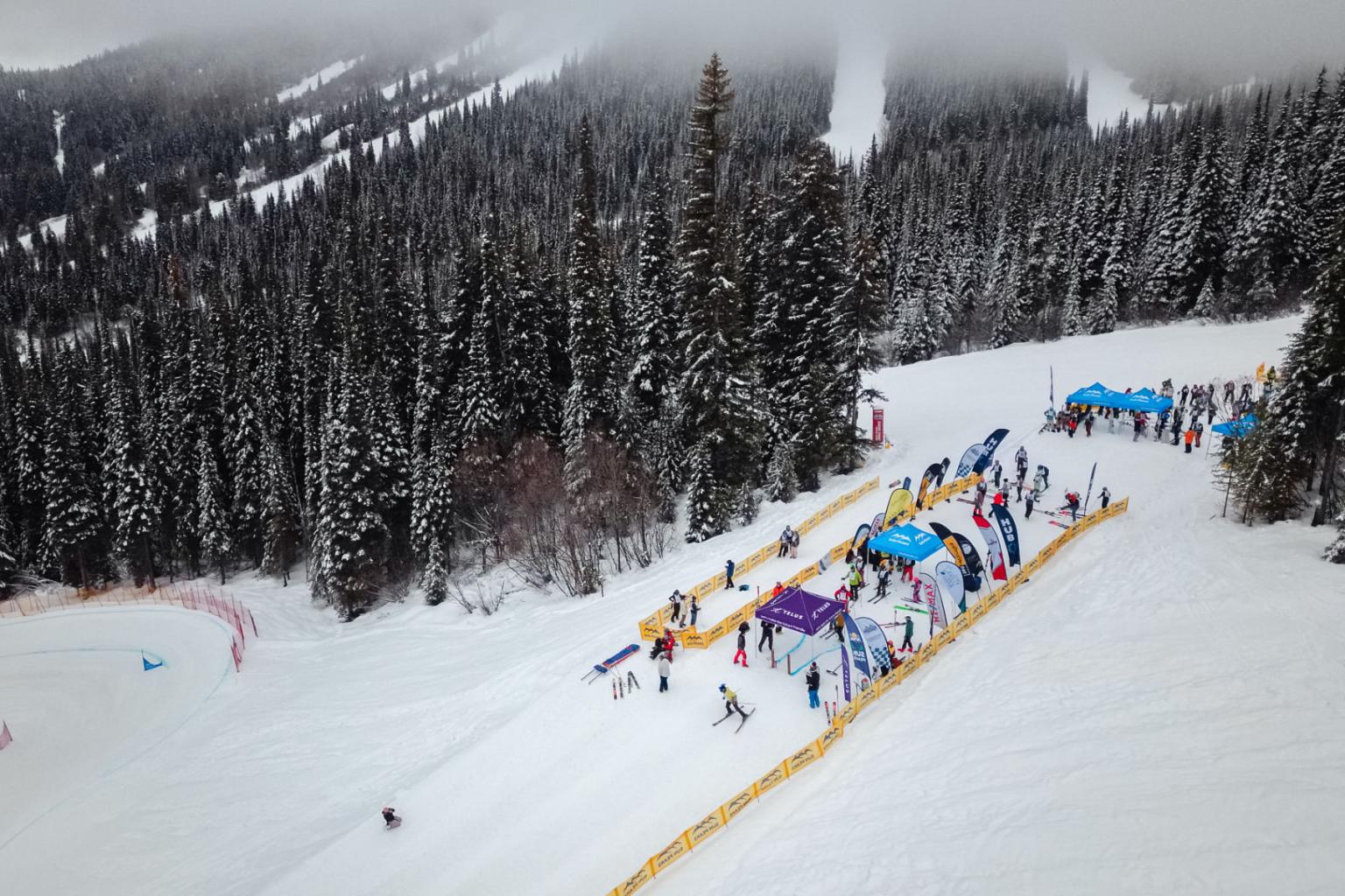 Skiers gathered at a colorful rail course on a snowy mountain slope.