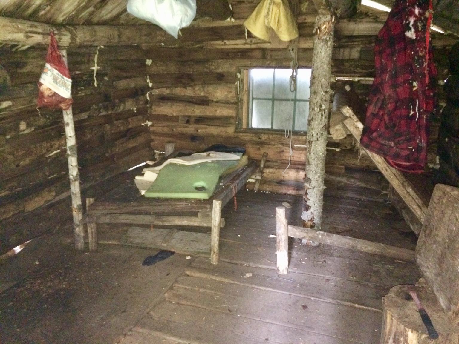 Interior of the Herder Cabin with old materials and bed still in place.