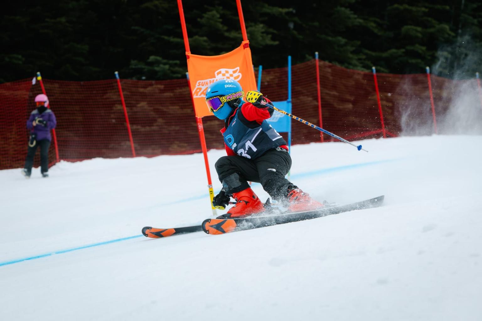 Young skier in blue racing through a snowy slalom course.