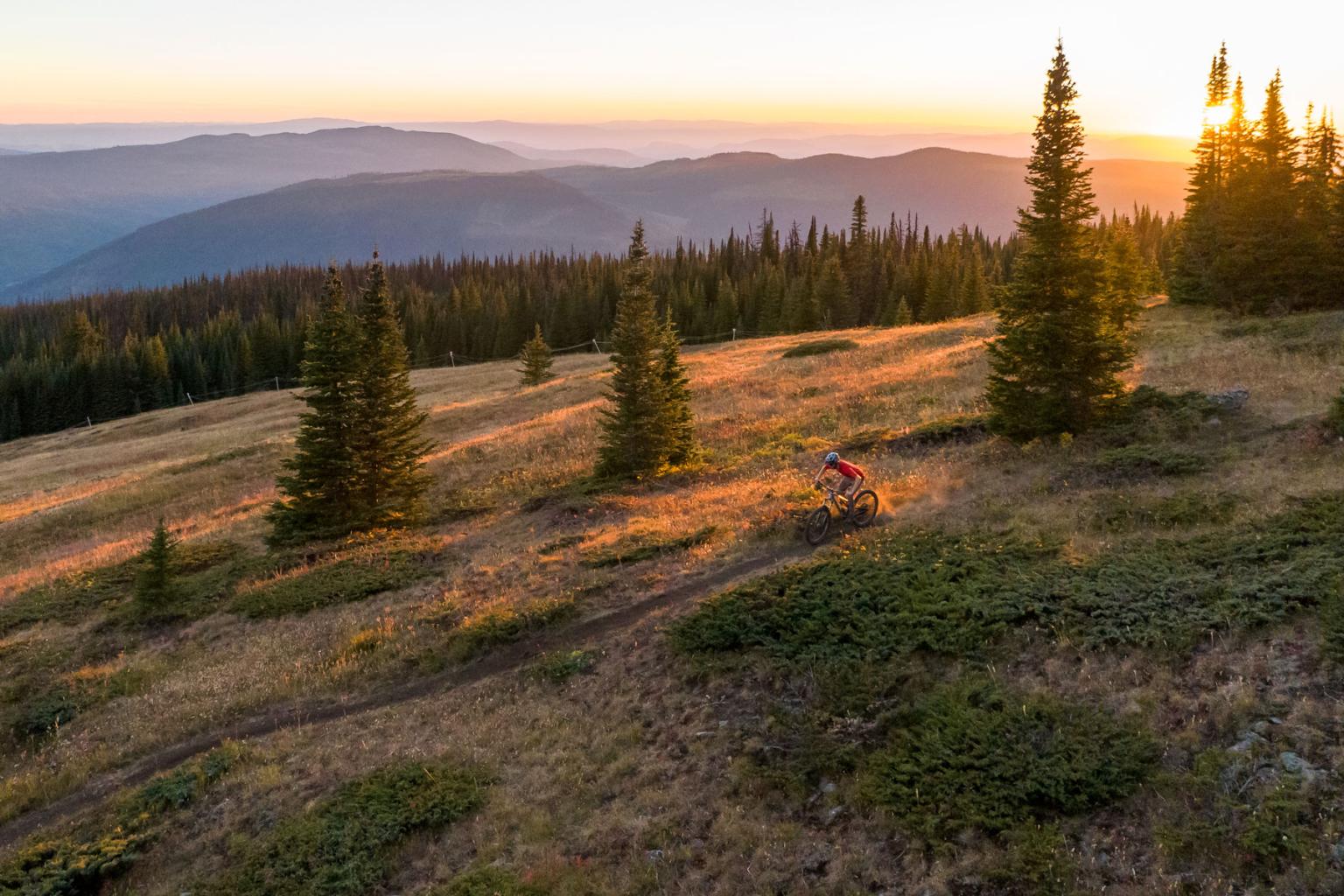 Biker riding on a trail with the sen setting behind