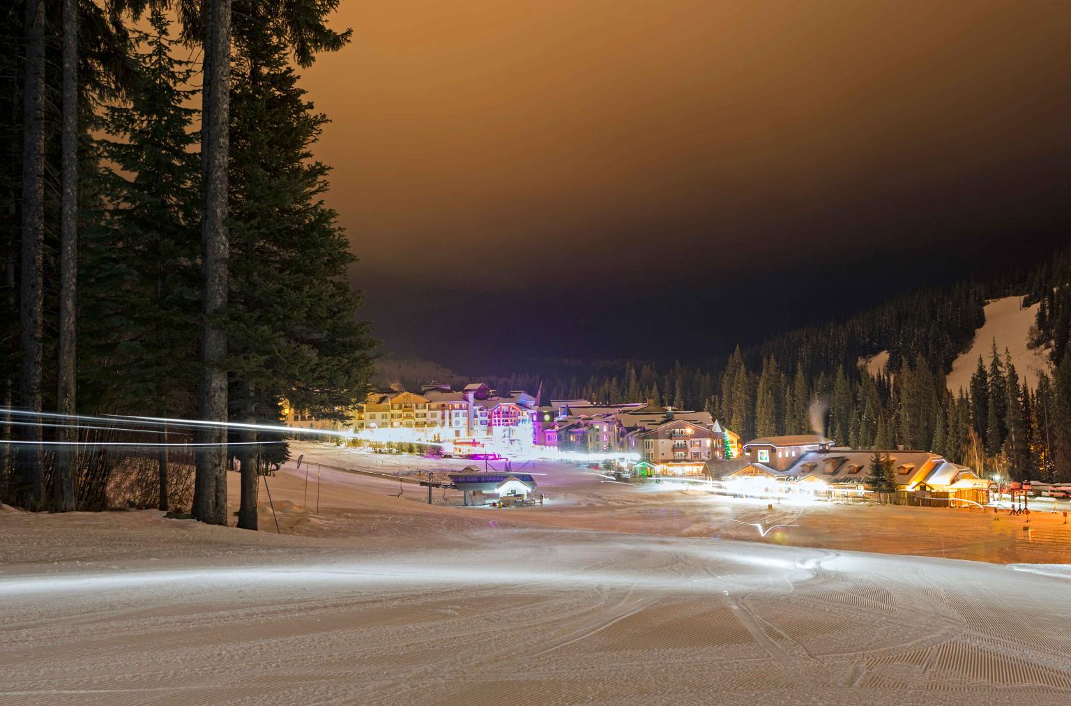 View of the village from a ski run at night with trees on the side