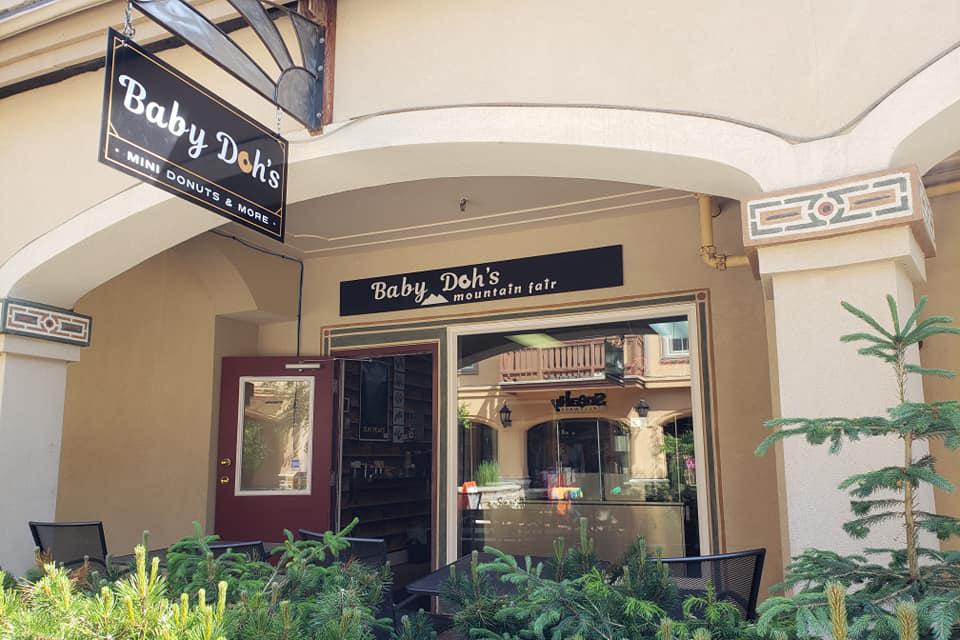 A view from outside of Baby Dohs in the summer with patio chairs and greenery