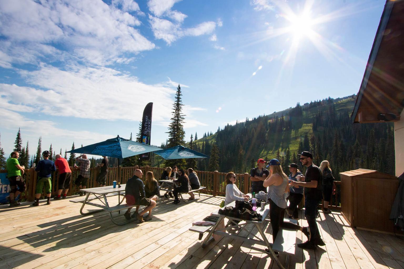 Patio with picnic tables and umbrellas with bikers and hikers