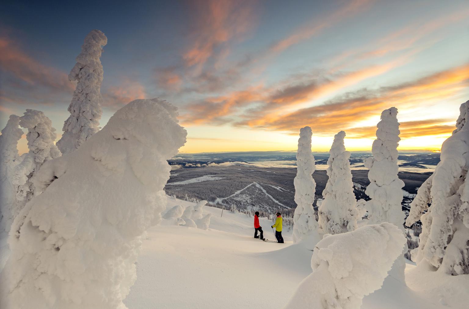 Skier and snowboarder standing surrounded by snow ghosts with village views