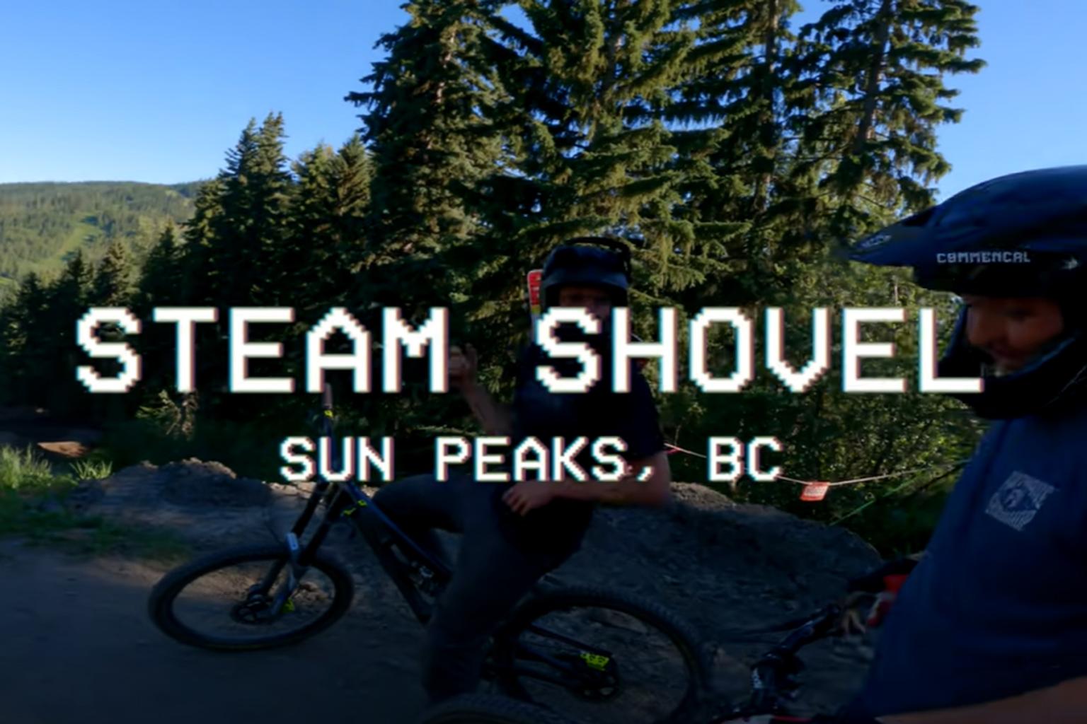 Two downhill mountain bikers on bikes with trees in the background