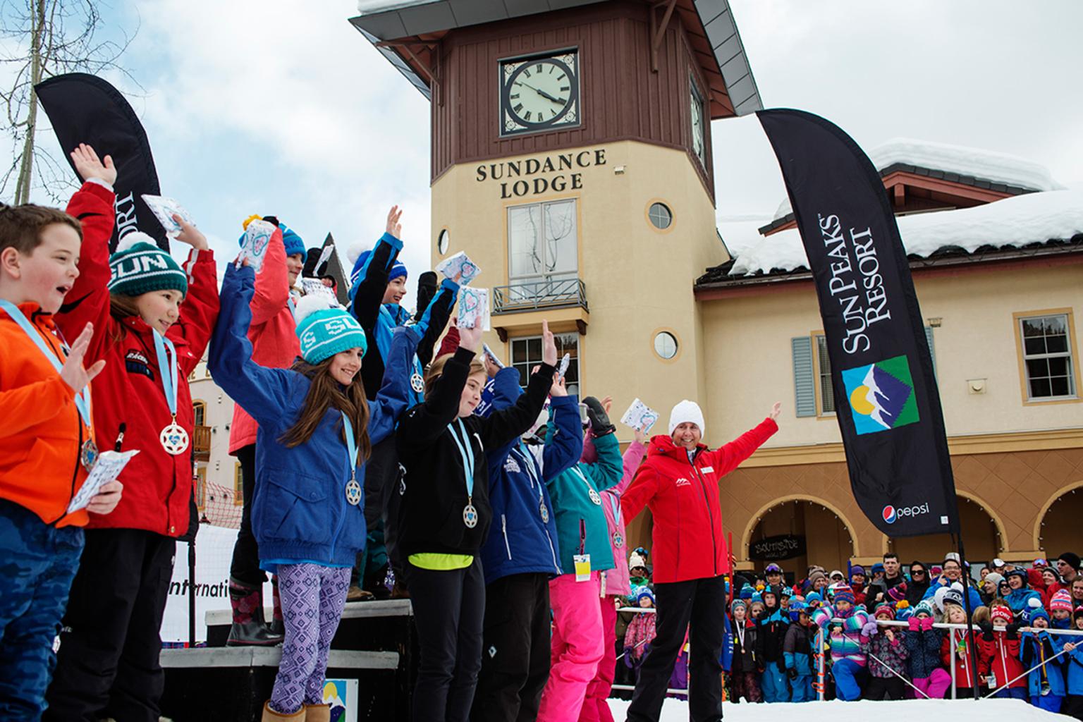 A group of people standing on a stage smiling beside the clock tower