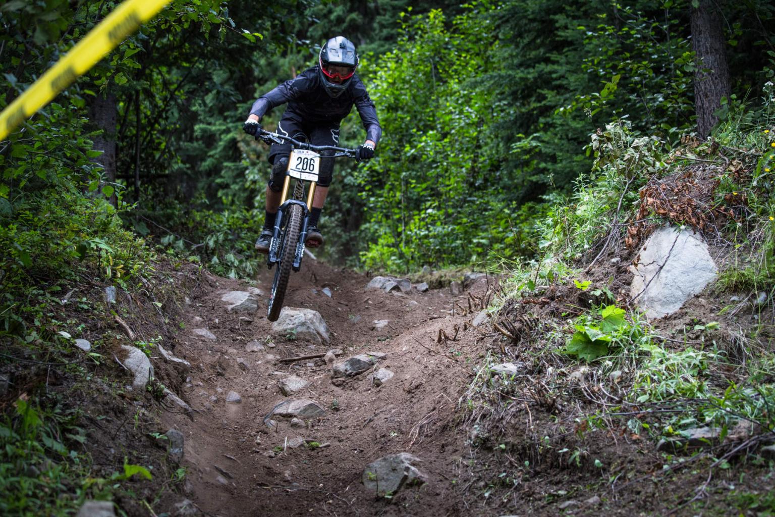 Downhill biker in the air on a rocky trail in the forest