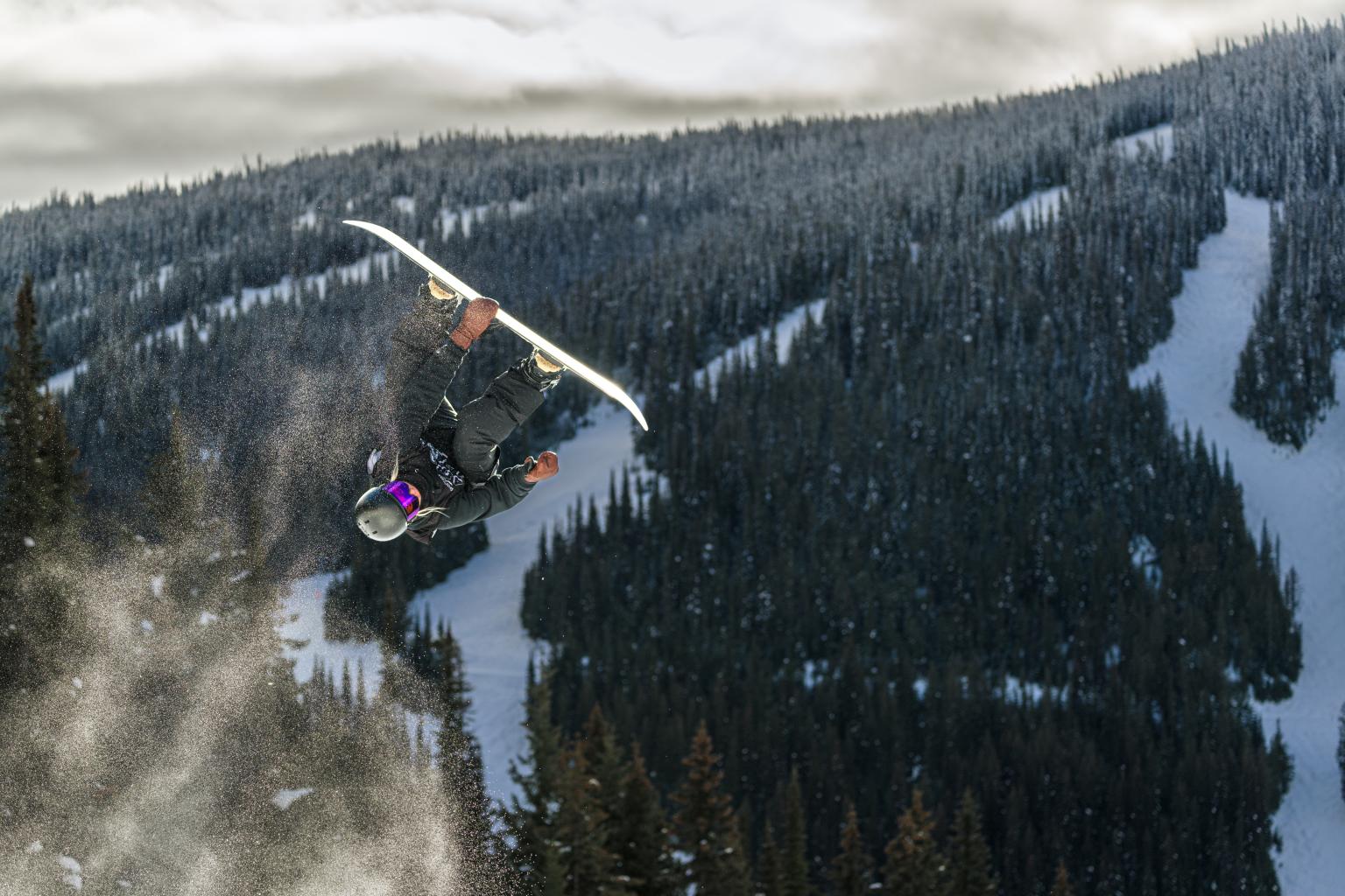 Snowboarder mid air with mountains in the background