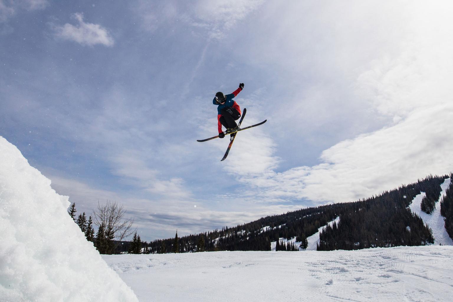 Skier in the air hitting a jump with mountain views behind them