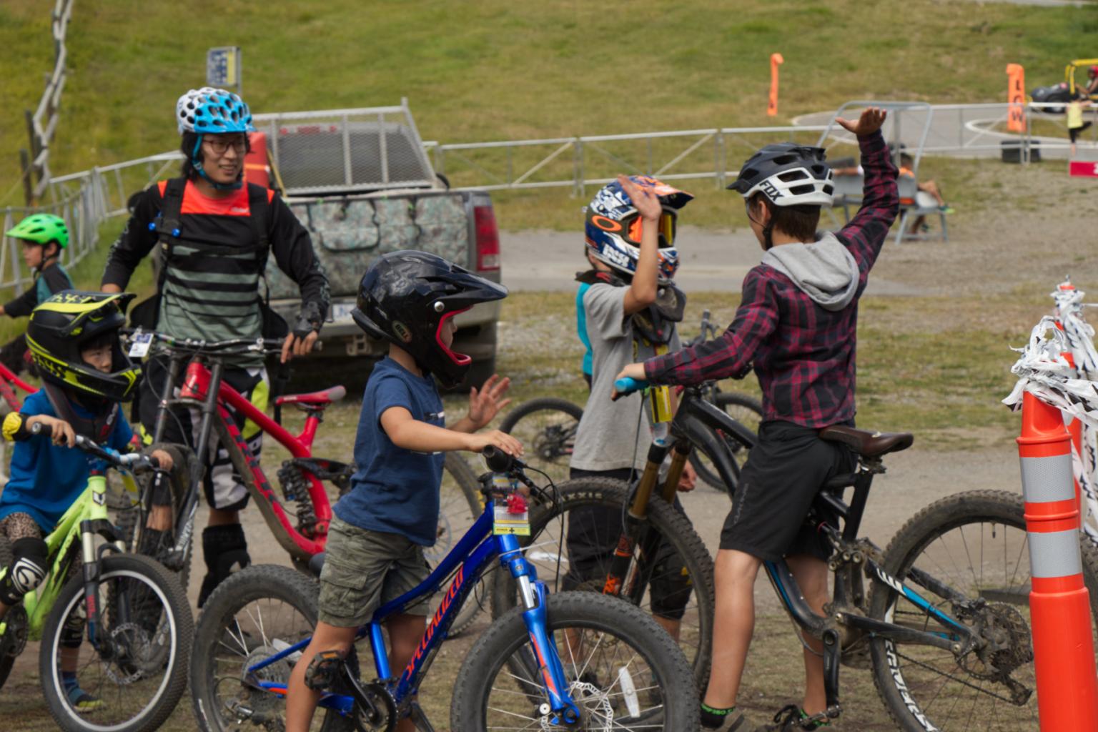 Children high-fiving while on bikes with other children around them
