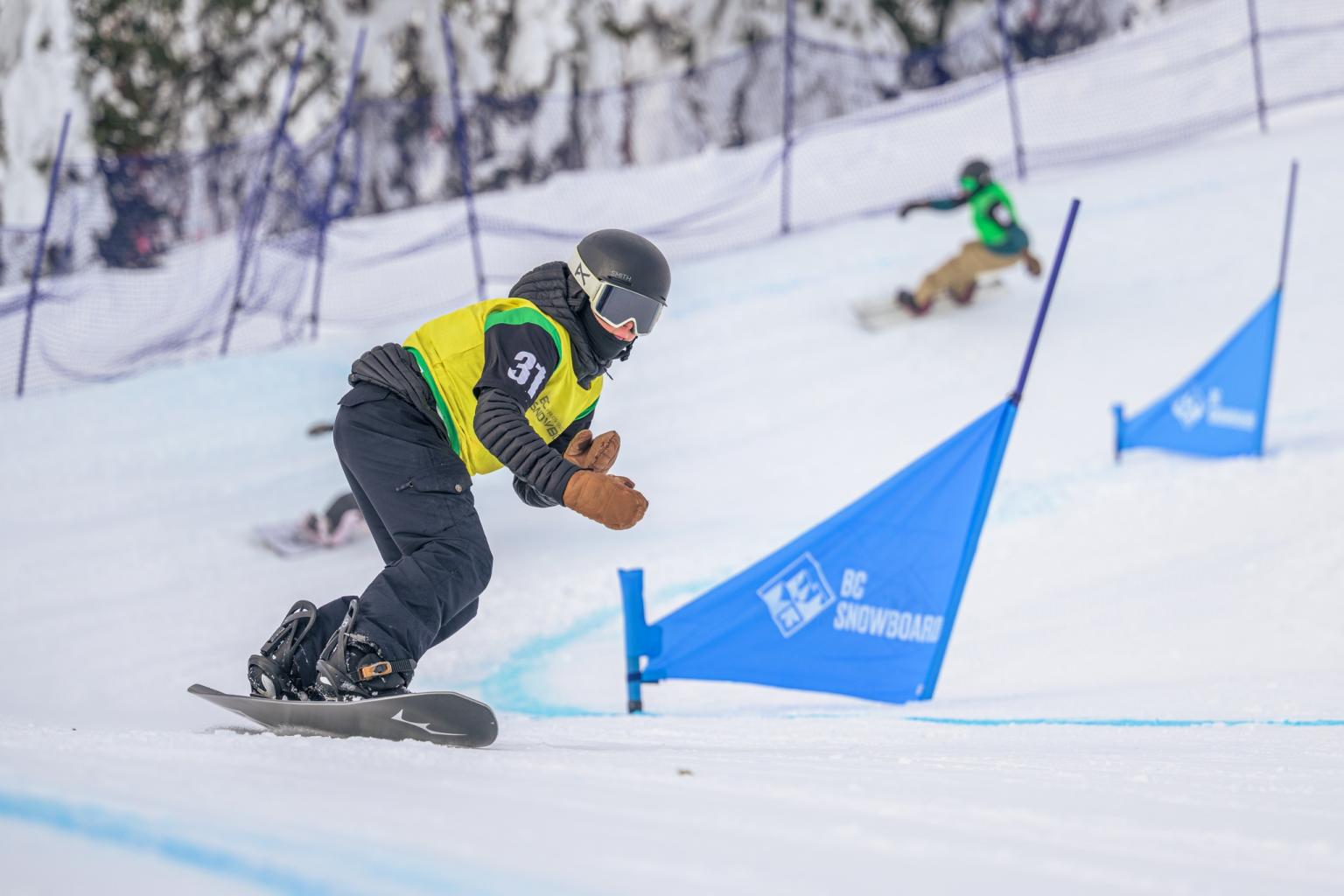 Snowboarder riding past a snowboard gate on a cross track