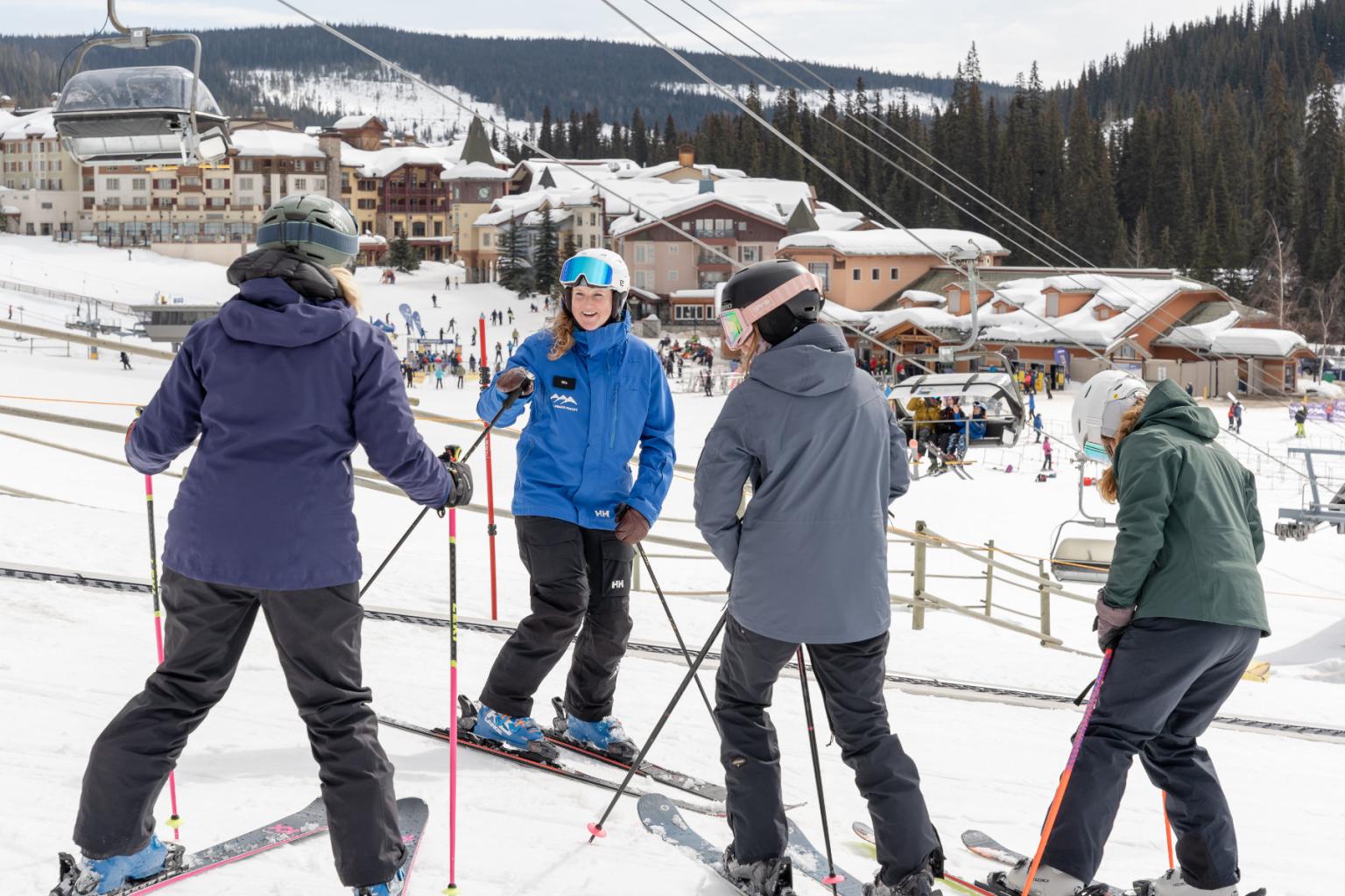 Four skiers in the learning zone with the village in the background