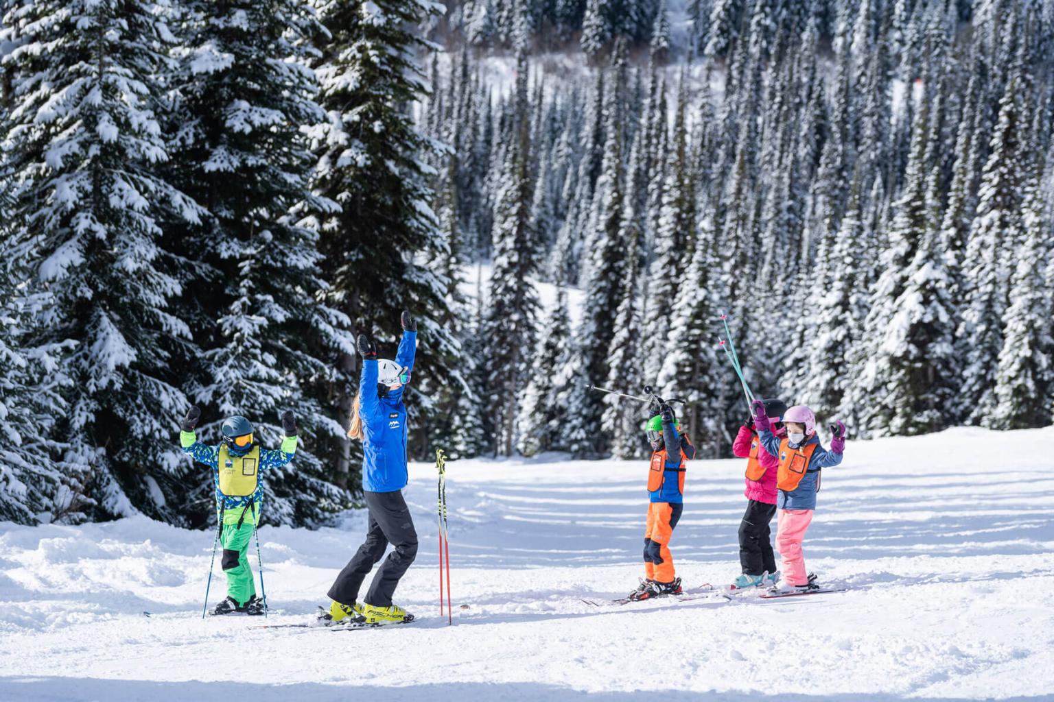 Four skiers standing on a run with trees in the background